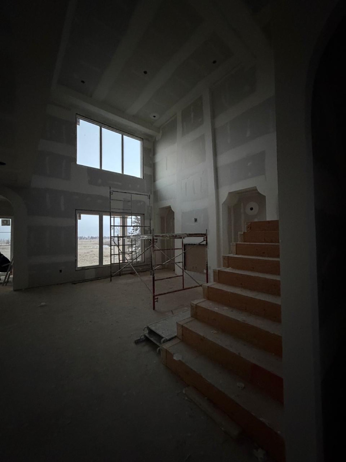 Two-storey foyer with staircase and arched drywall niches in a Calgary home