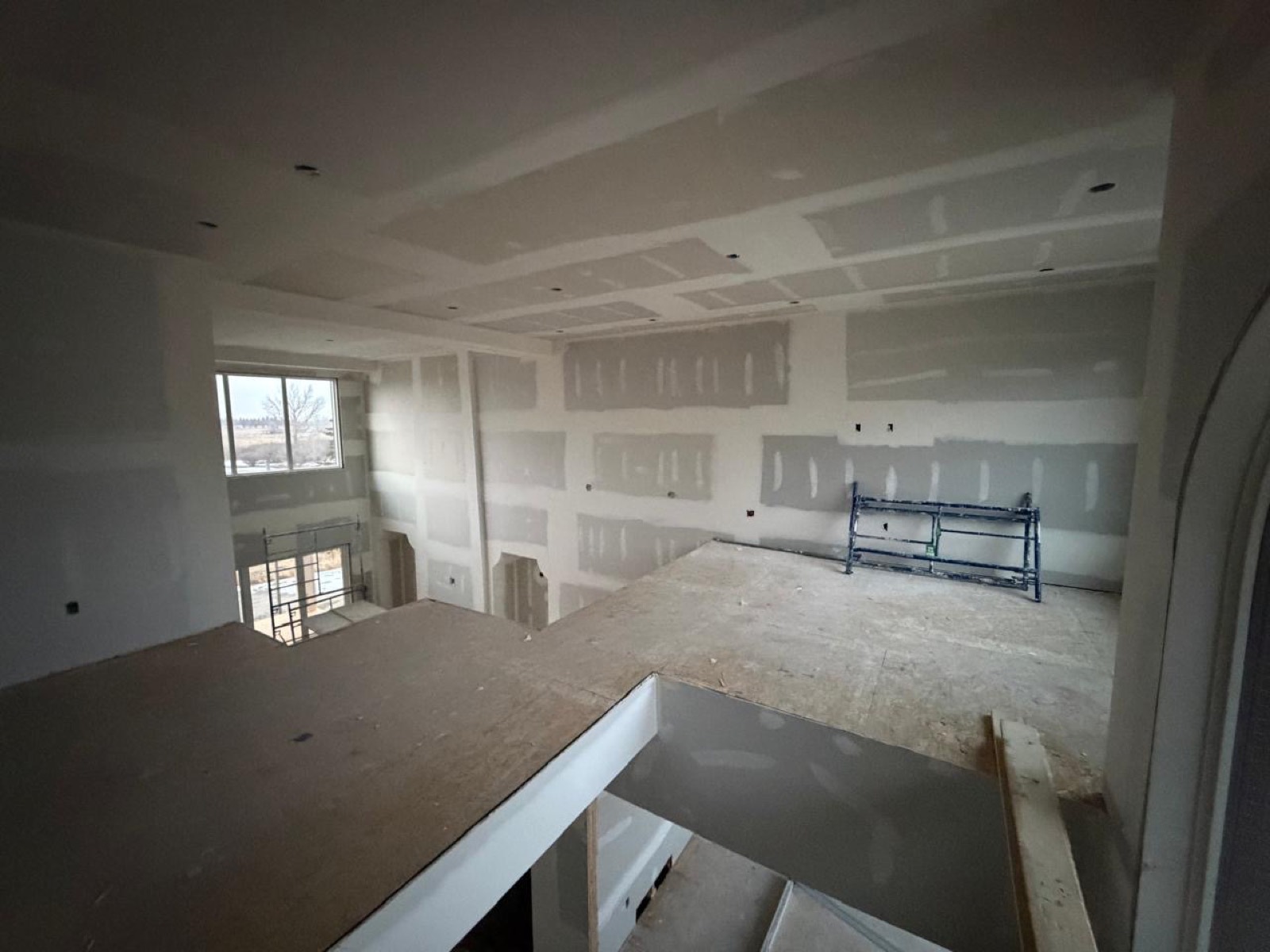 Open upper floor with taped drywall and coffered ceiling in a Calgary build