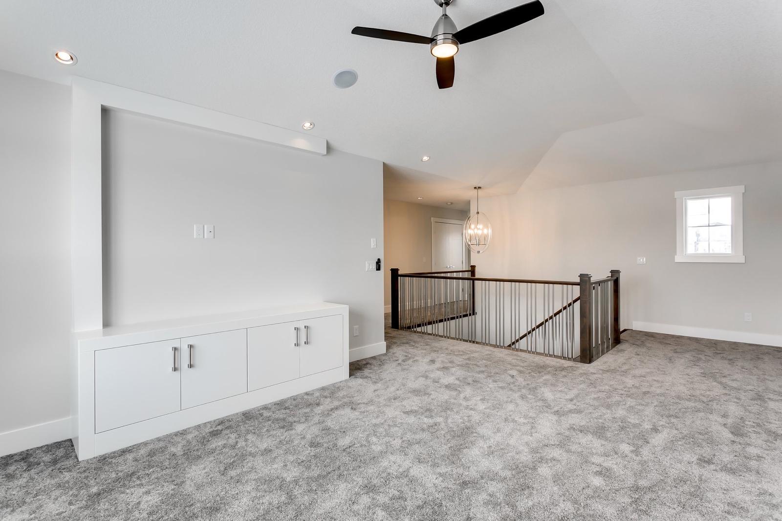 Finished upstairs bonus room with smooth drywall walls and staircase railing in a Calgary home