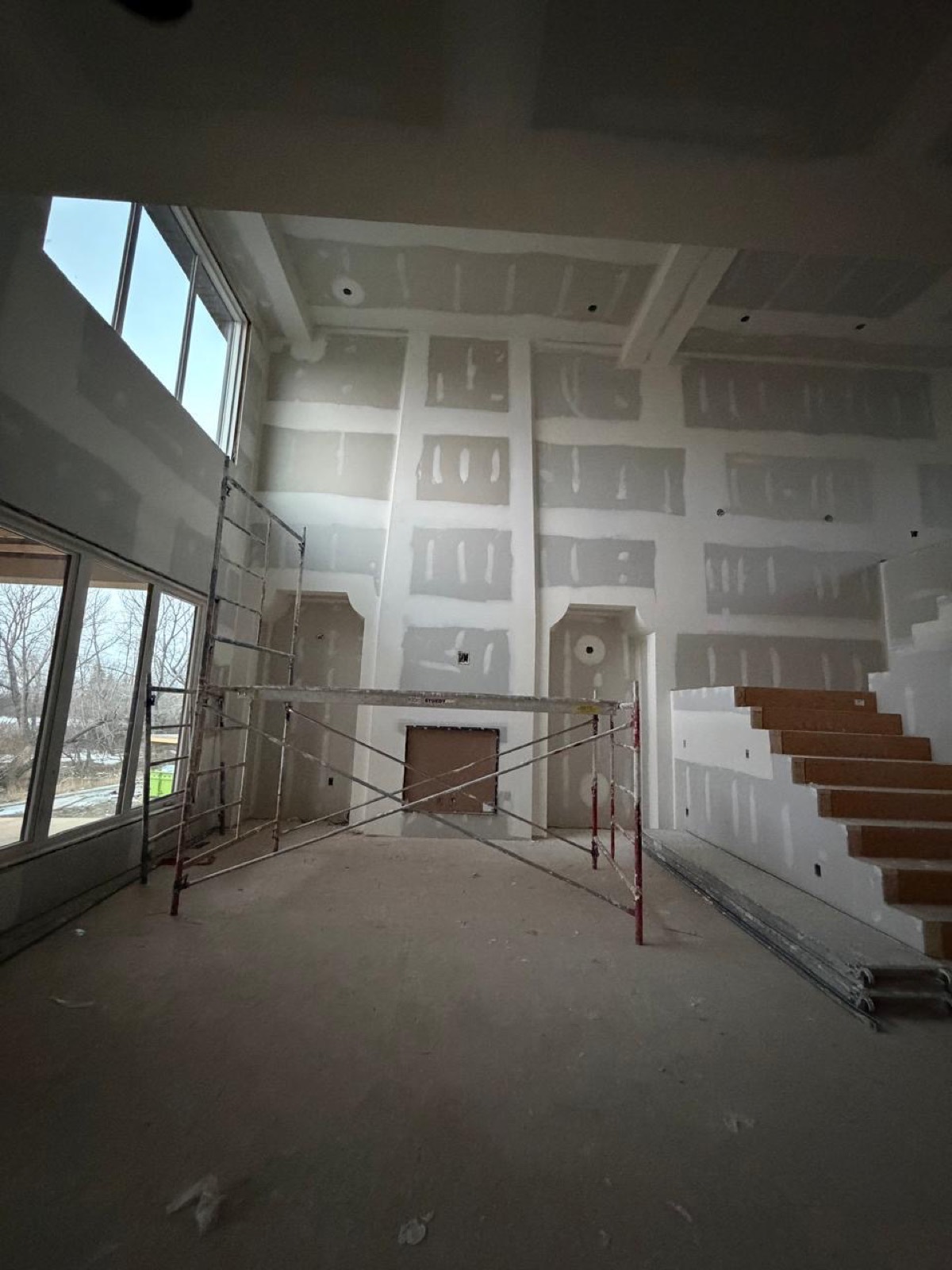 Two-storey great room with taped drywall and open staircase in a Calgary build