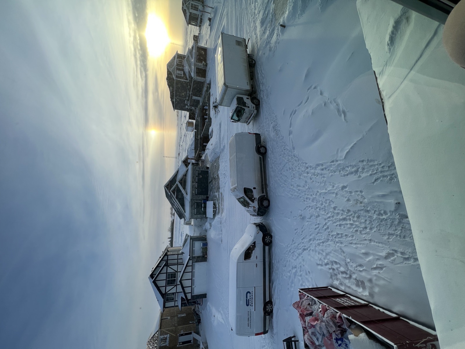 Shyam Drywall vans and box truck at a snowy Calgary jobsite at sunset